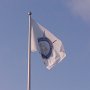 Golfhistoriska Sällskapets fana vajjar mot en klarblå himmel. 